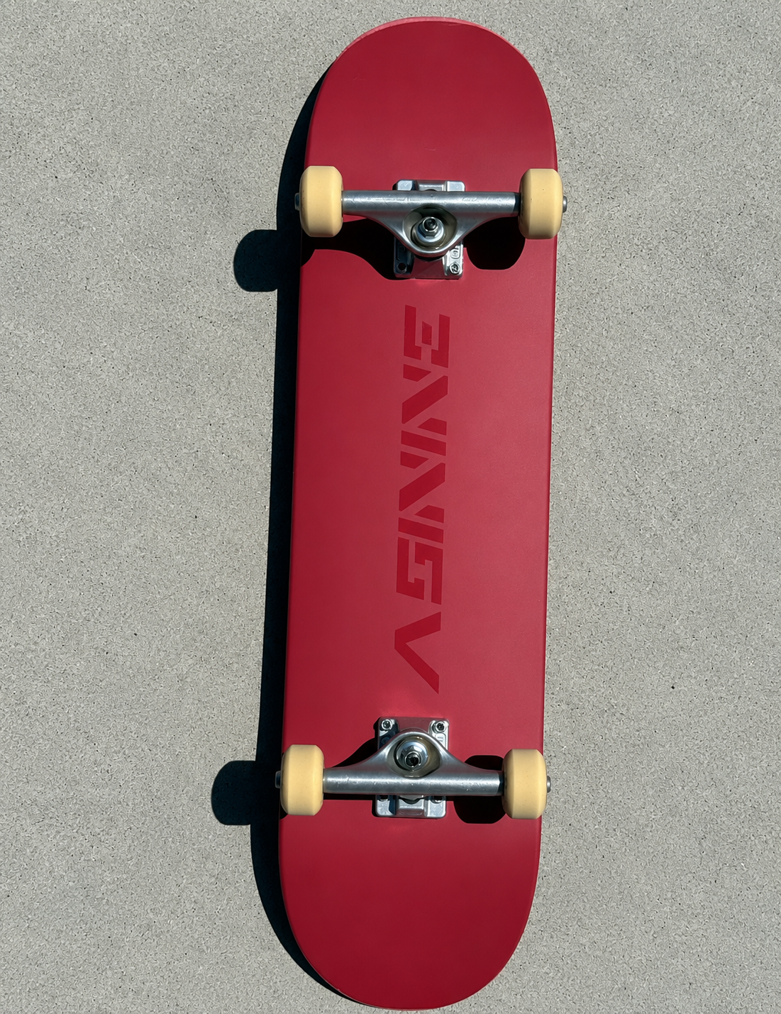 Complete Asinine skateboard with trucks and wheels installed, showing the satin red deck and high-gloss logo from above.