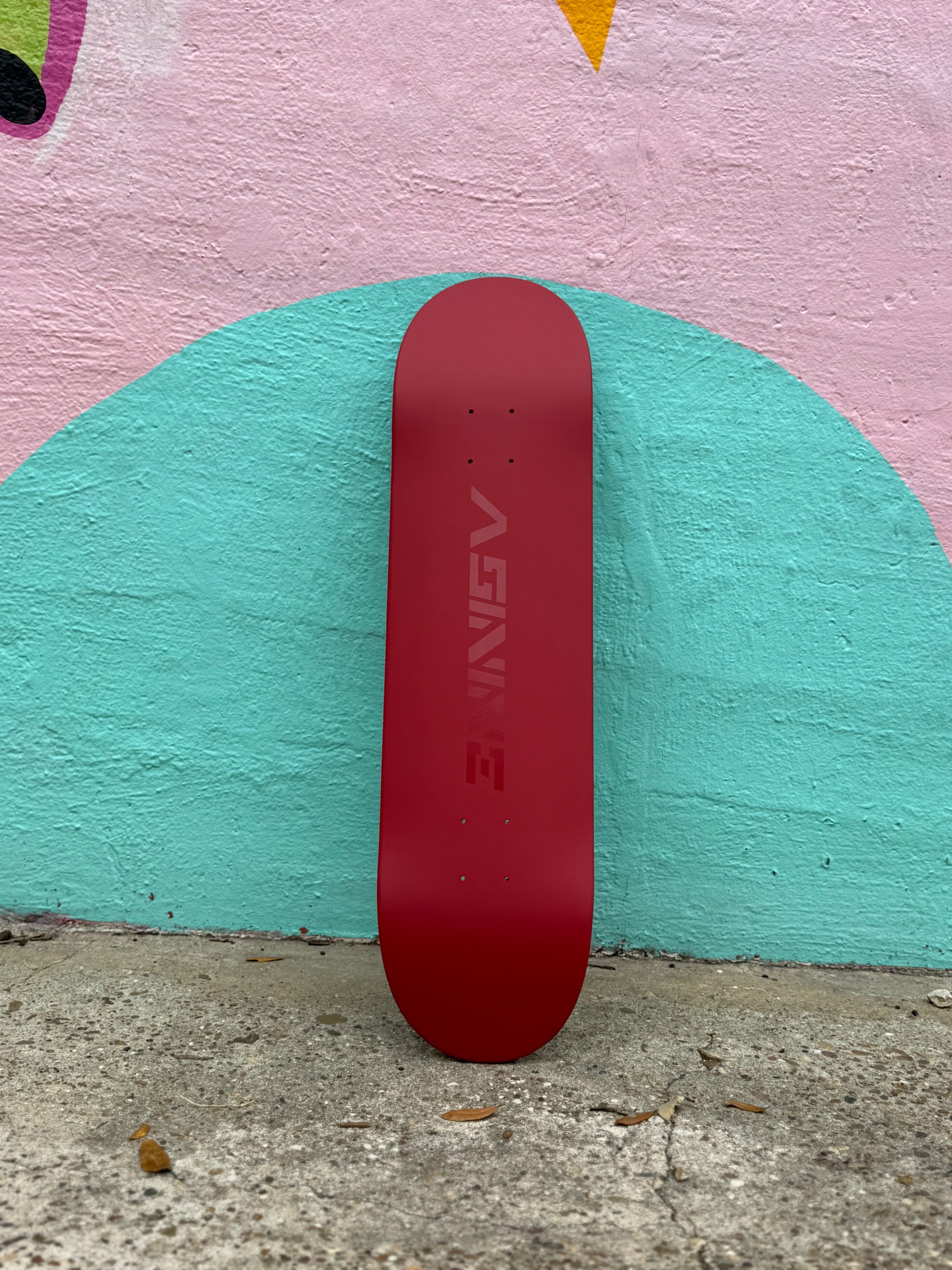 The Classic skateboard deck standing upright against a colorful mural, showcasing the satin red finish and high-gloss logo.